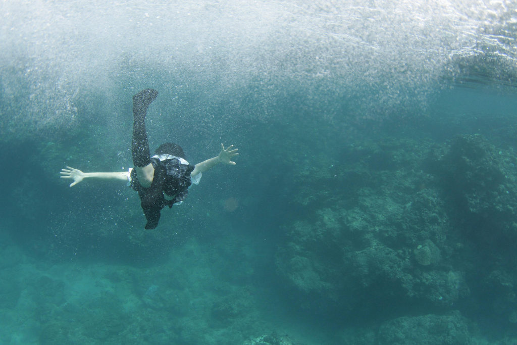 Une jeune fille nage dans la mer en uniforme dans Still The Water (2014) de Naomi Kawase